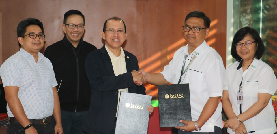 Dr. Gregorio (center) and Dr. John C. De Leon (second from right) shake hands after signing the MOU. Also in the photo are Mr. Florendo (second from left), Dr. Barroga (rightmost), and Dr. Pedcris M. Orencio, SEARCA Program Head for Research and Development.