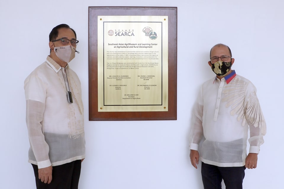 Sec. Dar and Dr. Gregorio by a brass marker on which is inscribed information on the partnership of SEARCA and DA-BAR in the construction of the Southeast Asian AgriMuseum.