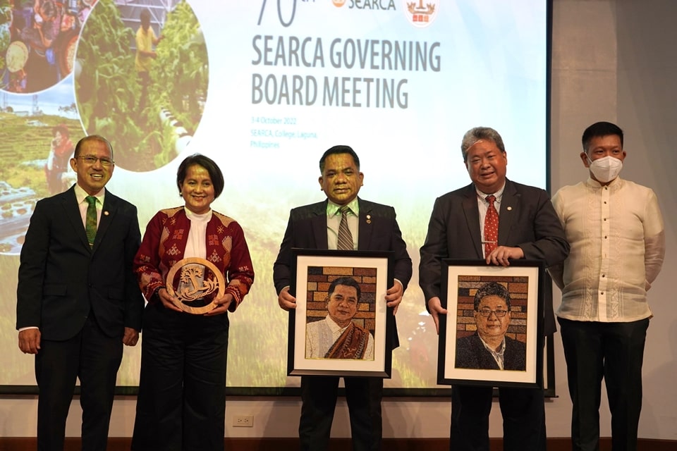Dr. Ballesteros holds a wooden SEARCA Tree while Dr. Camacho and Assoc. Prof. Dr. Tim each holds a rice portrait of themselves respectively handed over by Dr. Gregorio and Assoc. Prof. Florendo.