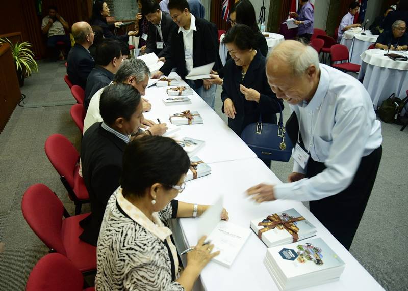 Attendees of the book launch have their complimentary copies signed by the authors and editors.