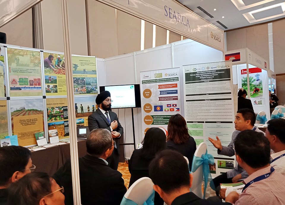 At the SEARCA knowledge and learning booth, Thailand Permanent Representative to IFAD and Minister of Agriculture Thanawat Tiensin (seated right) shares Thailand's experience during the case presentation of IFPRI-SEARCA's ATMI project by IFPRI's Manmeet Ajmani, Research Analyst (standing).